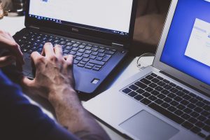 Hands typing on 2 laptops